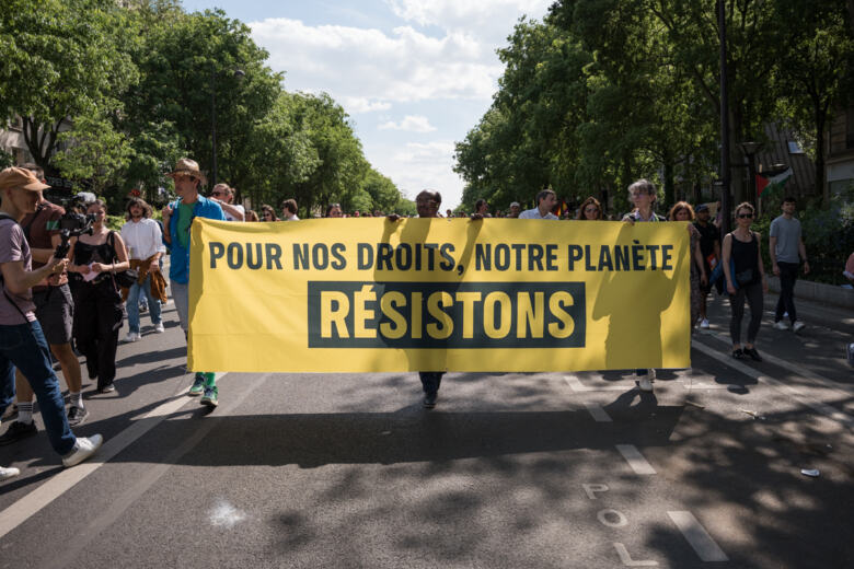 Cortège Greenpeace lors la manifestation du 1er mai à Paris, avec une banderole : "Pour nos droits, notre planète : résistons !"