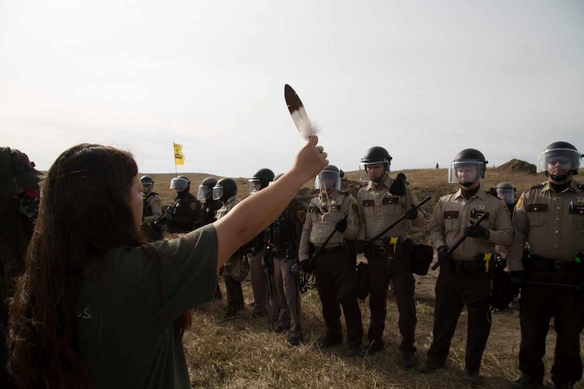 Protest at Standing Rock Dakota Access Pipeline in the US. - A phalanx of National Guard and police advance toward a water protector holding an eagle feather at a camp near the Standing Rock Reservation in the direct path of the Dakota Access pipeline (DAPL) where 117 people were arrested.
